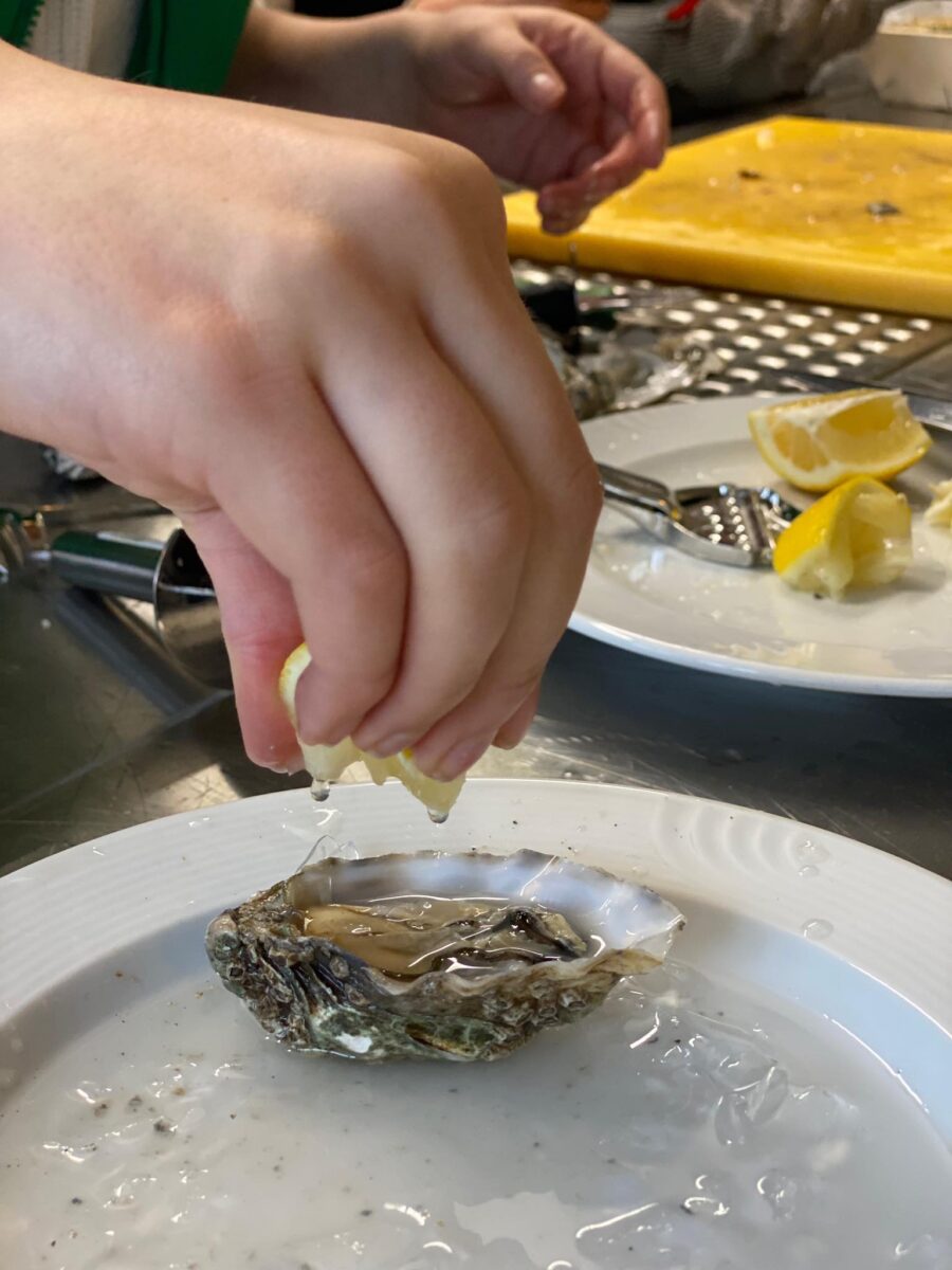 Zitronensaft wird auf Austern ausgepresst. 