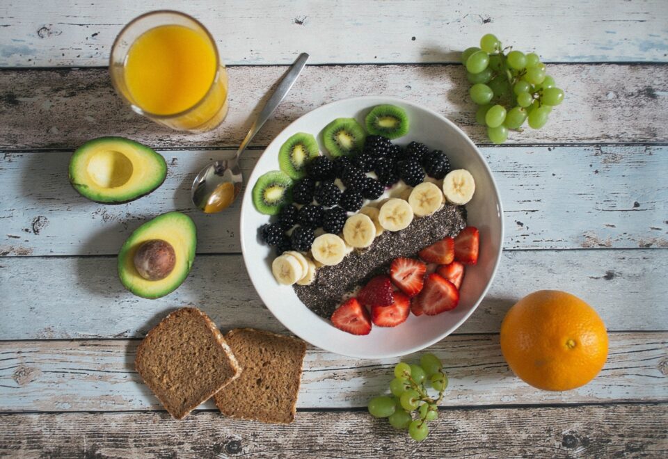 Fruchtschale mit aufgeschnittenem Obst, Brot, Avocado, Saft