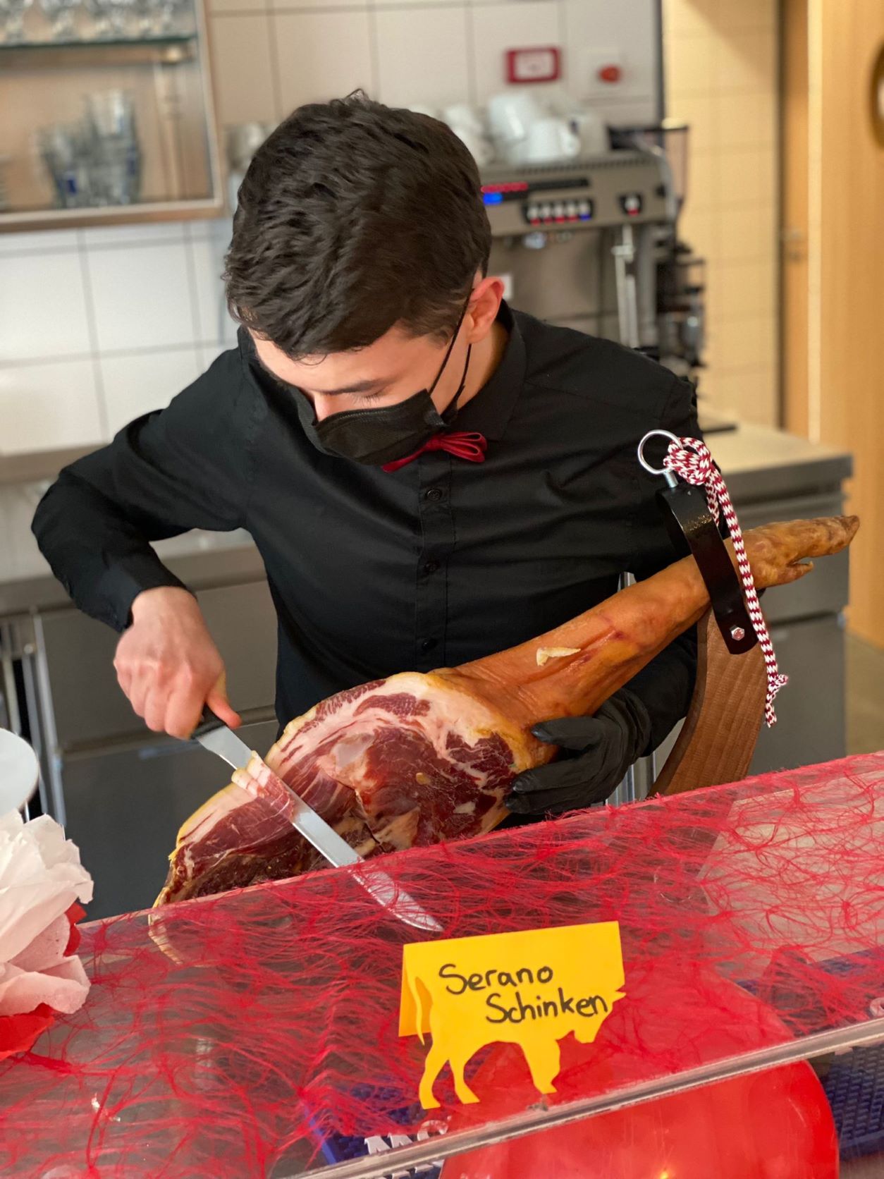 Tom Windisch (10. Klasse) schneidet Serrano Schinken für unsere Gäste