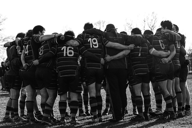 Sportteam einer Schule von hinten abgebildet, das sich gegenseitig in den Armen hält